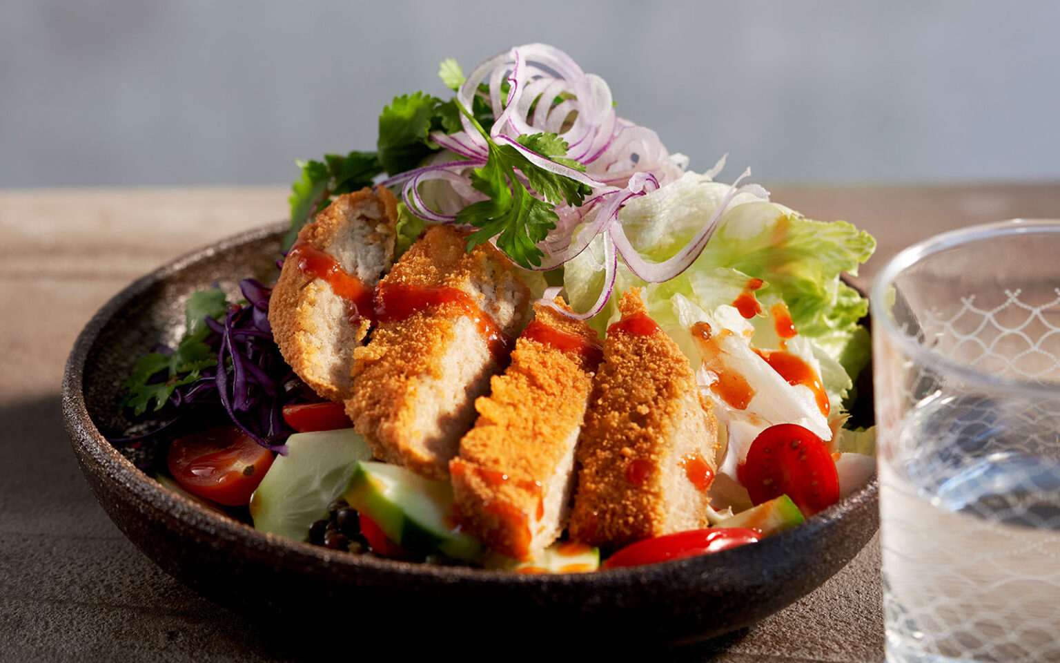 Anamma Vegoschnitzel ligger skivad uppe på en bowl med sallad och grönsaker.