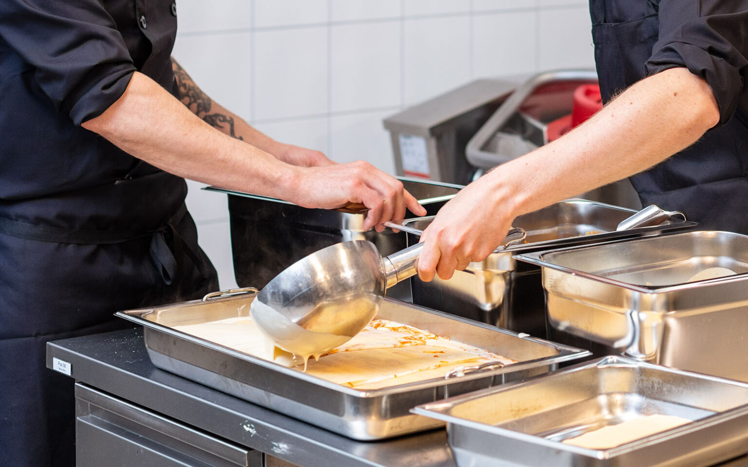 Kockhänder som jobbar med en lasagne.