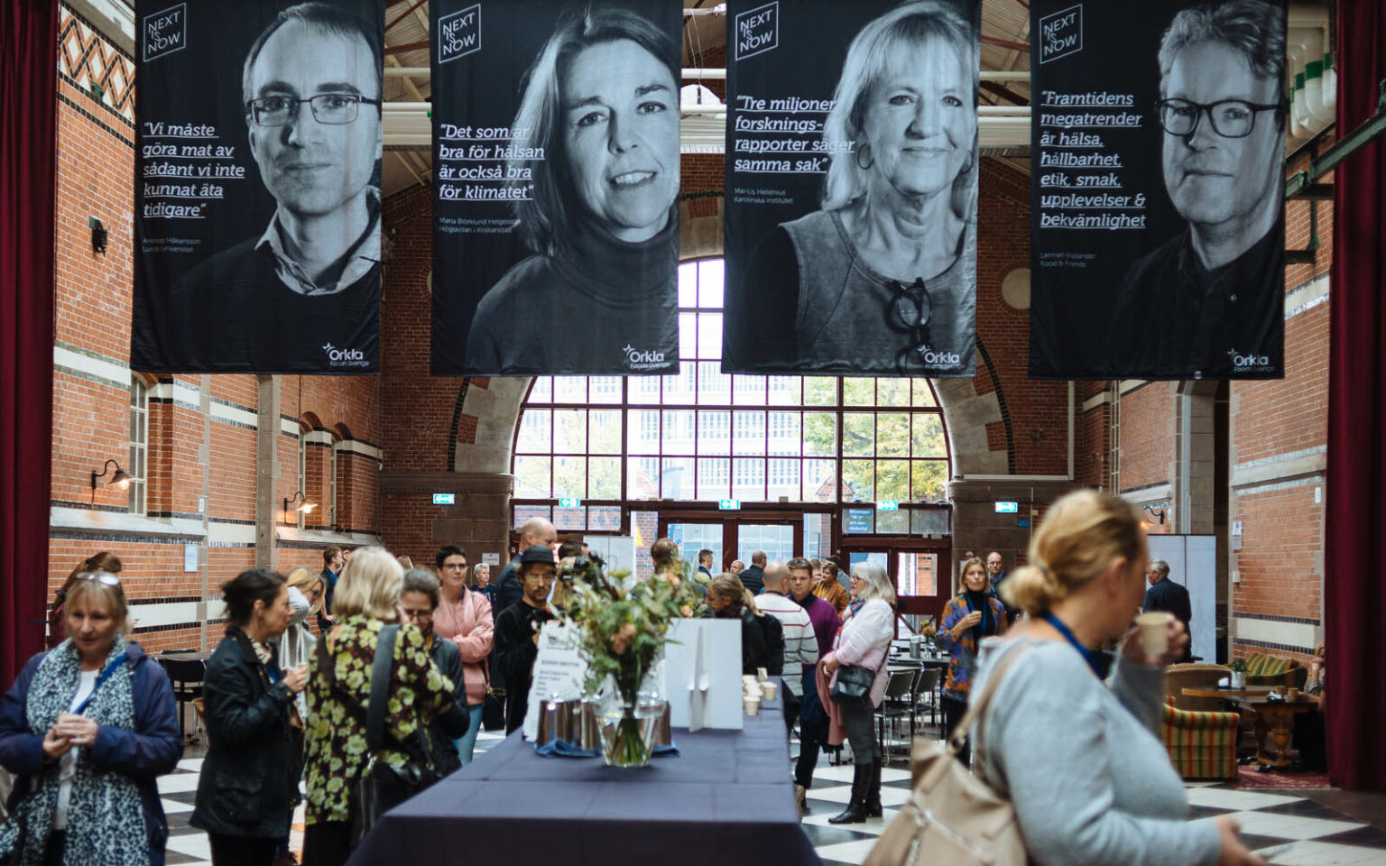 Eventhallen med deltagare på golvet och stora vepor i taket.