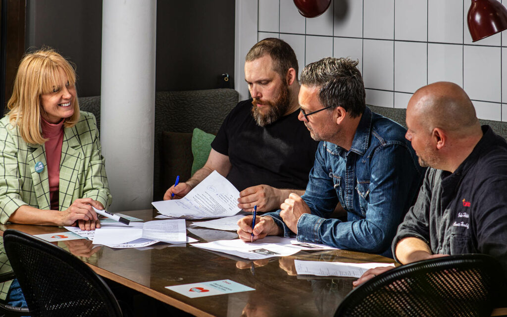 Fyra personer sitter vid ett bord och planerar.