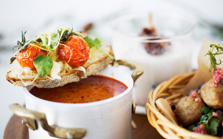 Gulaschsoppa i en vit kastrull, med en tomatmacka vilandes på kanten.