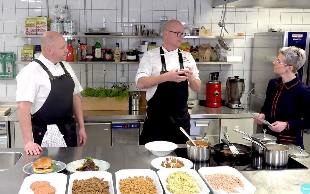 Kockarna Johan och Johan står med Ann vid köksbänk. Förklarar och utbildar om flera vegetariska produkter.
