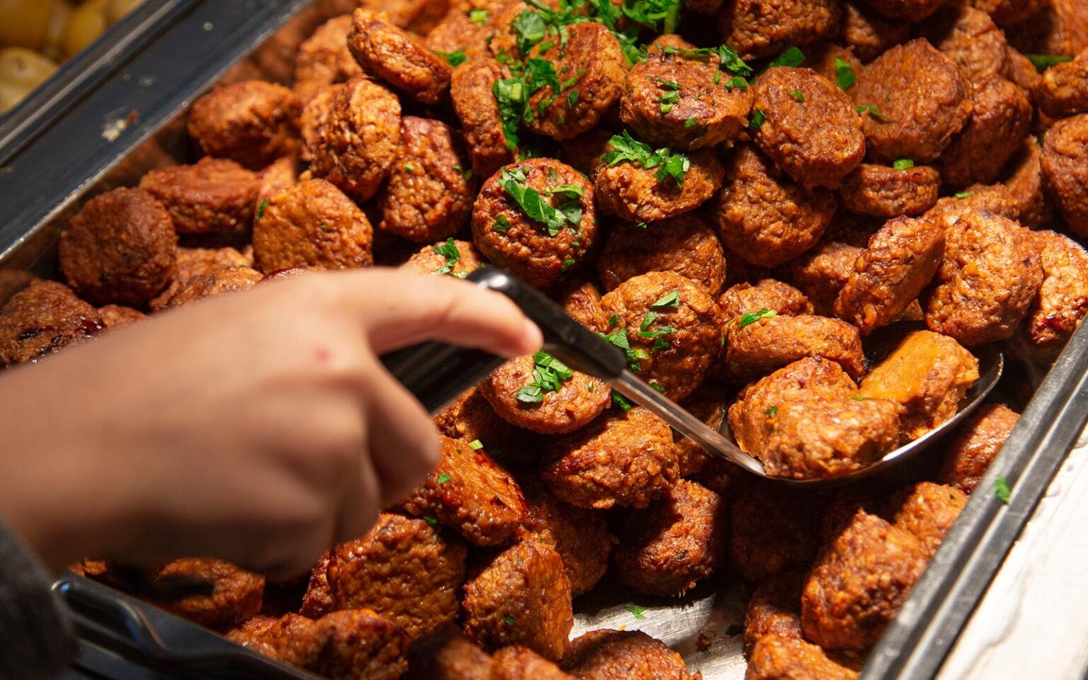 Hand som håller i slev, och rör bland bullar gjorda på Anamma Formbar Vegofärs.