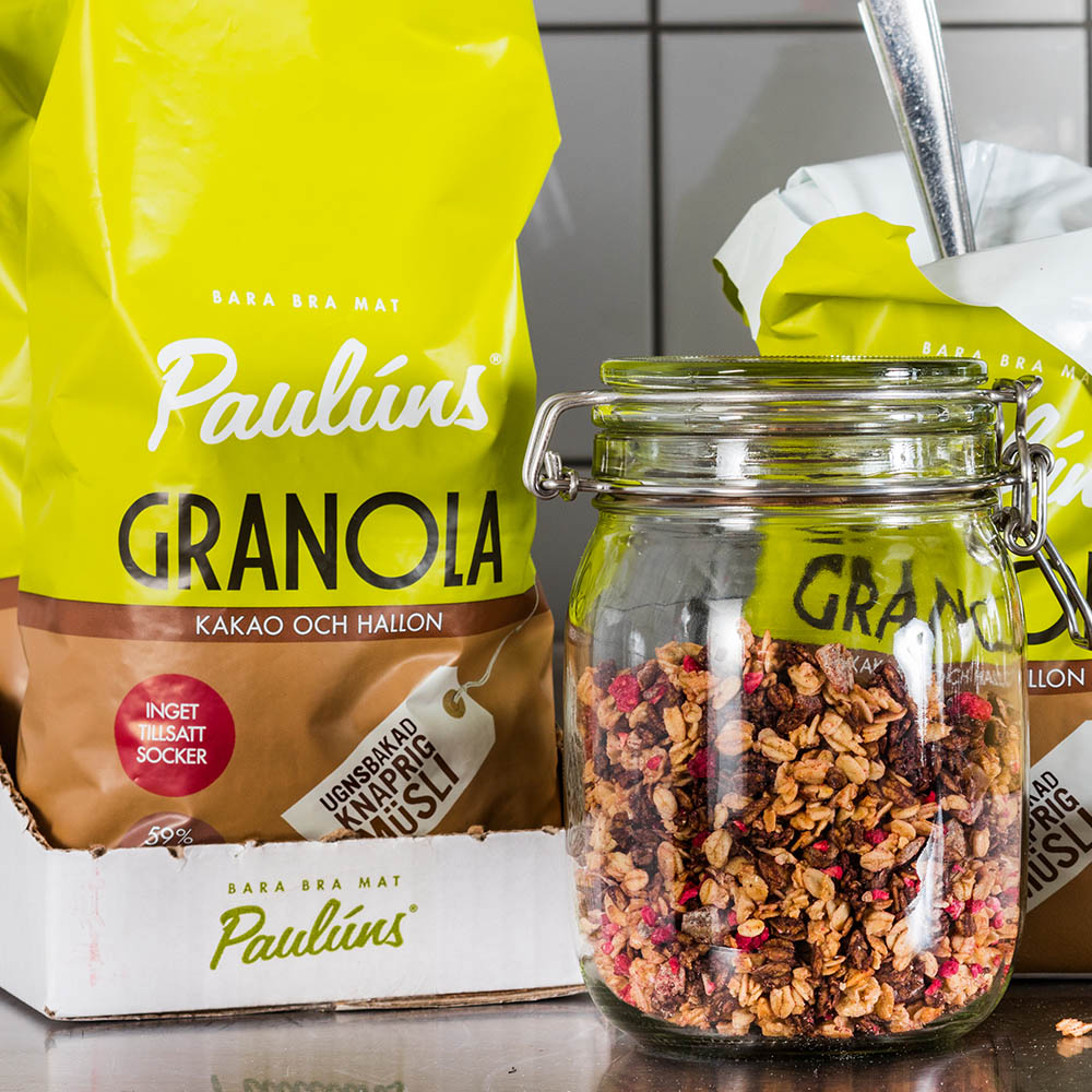 Förpackningar med Paulúns Granola. Framför står en glasburk med granola.