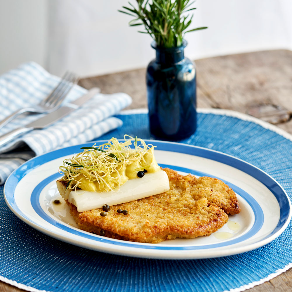 Tallrik med Lecora Pankopanerad Schnitzel på ett blått underlägg.