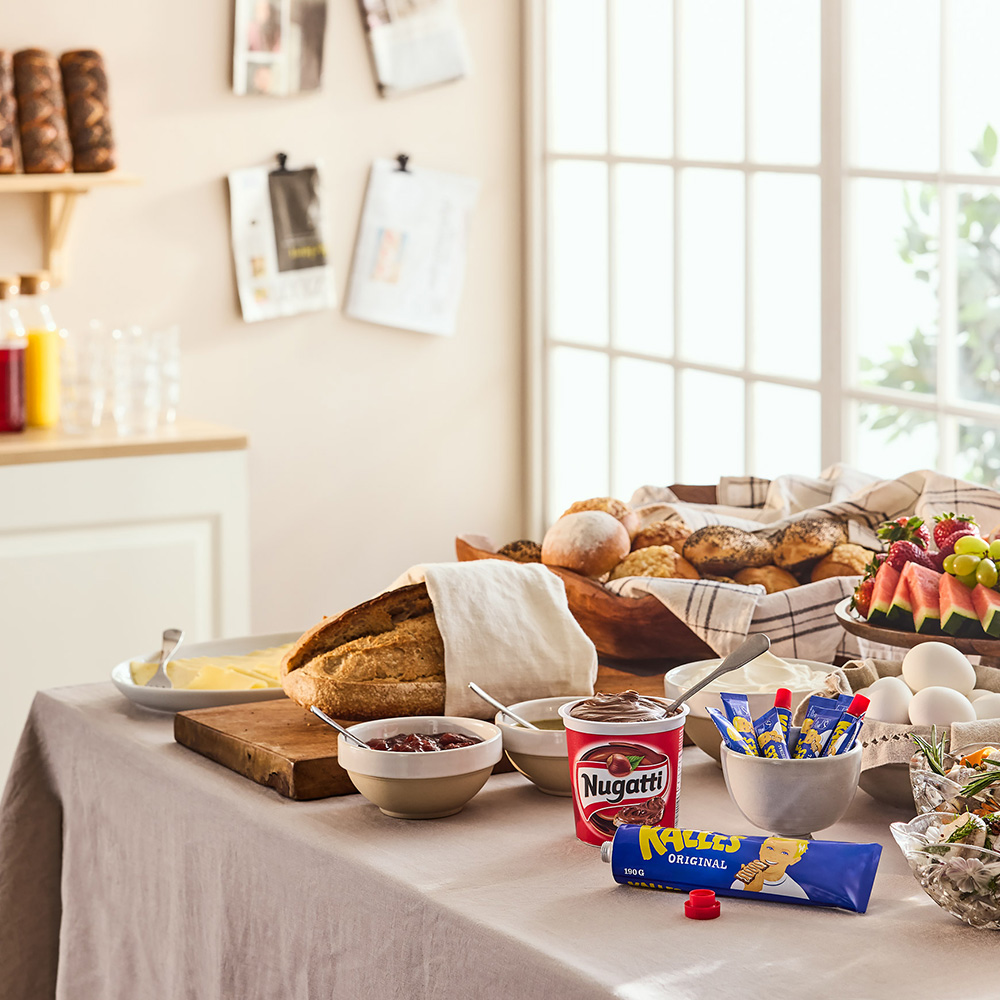 Frukostbuffé uppdukad framför fönsterparti i ljus miljö.
