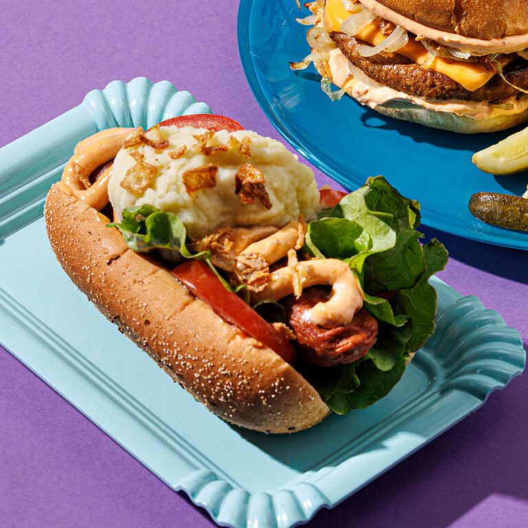 Potatismos, sallad och dressing serverad på en varm korv med bröd.