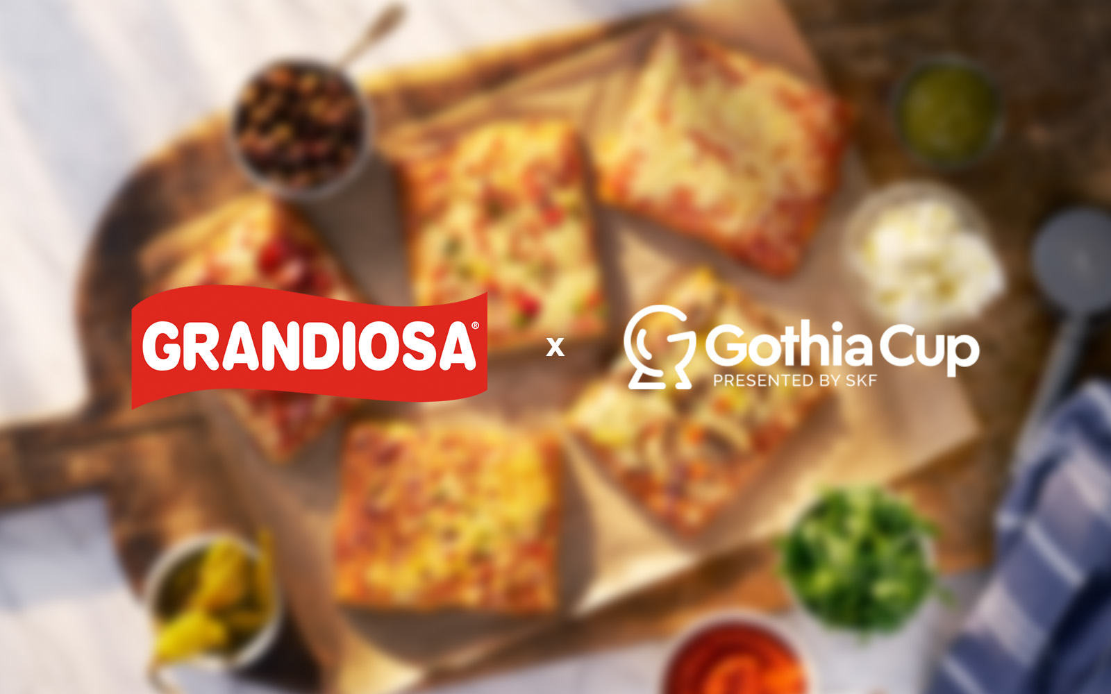 Grandiosa-logga och Gothia Cup-logga mot en bakgrund av fyrkantspizza som är i oskärpa.