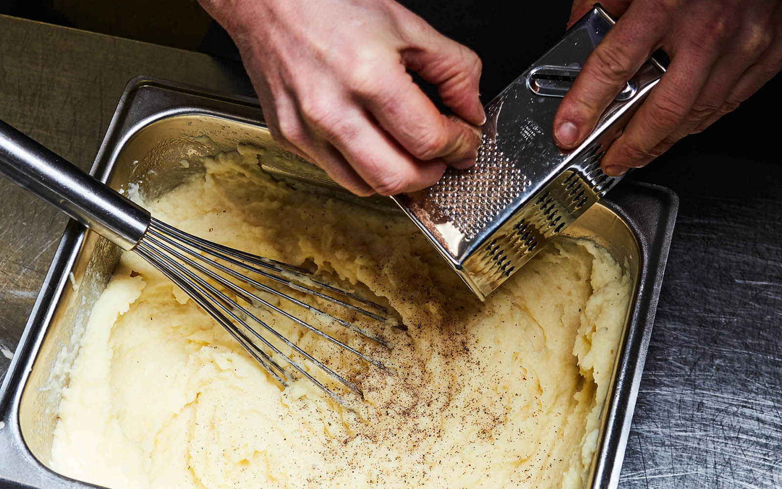 Kockhänder som river ner muskot i FELIX Potatismos.